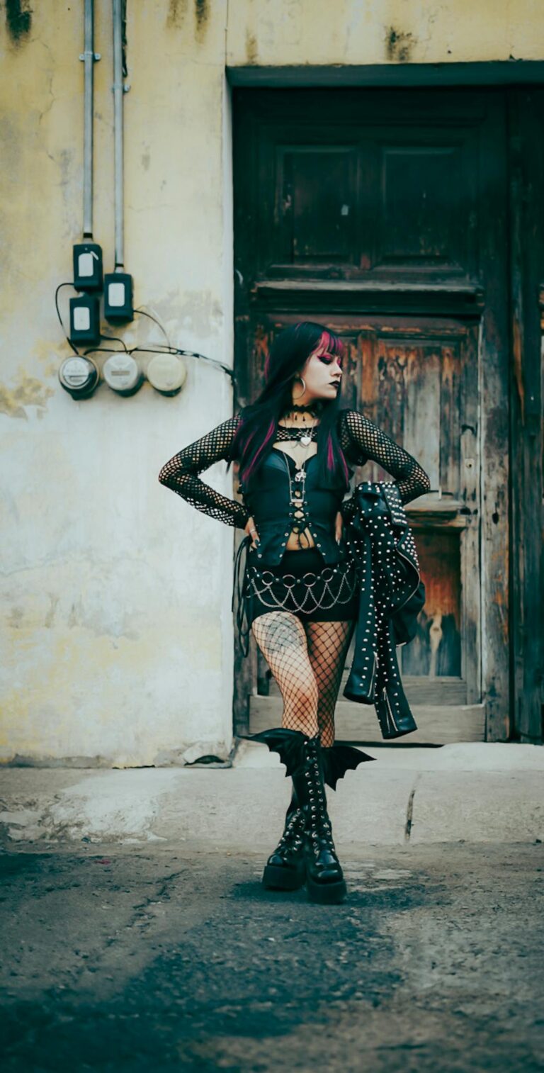 Stylish gothic woman posing against an old wooden door in an industrial urban area.